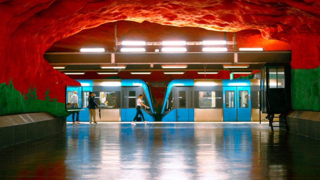 Vibrant artwork at a Stockholm metro station with people and a blue train.